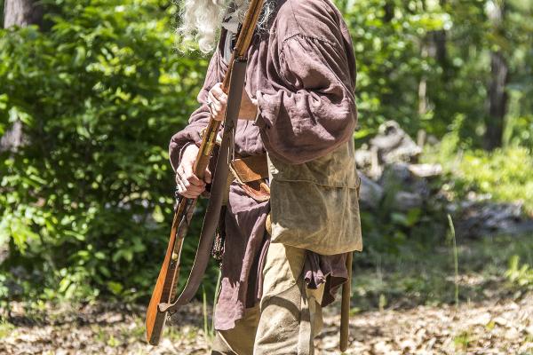 A patriot rifleman stands ready to fire his weapon.