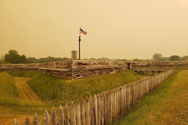 An eerie yellow, hazy sky surrounds the wooden fort. It makes it look strange.