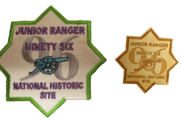 Both the embroidered Junior Ranger patch and the wooden badge are in the shape of an 8-pointed star.