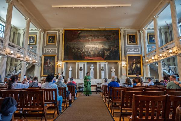 Photo of Rangers dressed in historic clothing in a large room with lots of people watching