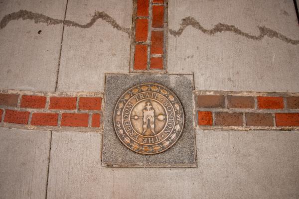 Three double brick lines in the ground meet at a medallion for the Freedom Trail.