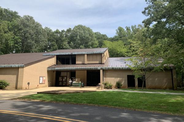 Modern brown building surrounded by trees, park ranger standing in front