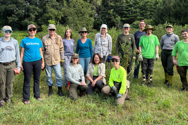 A group of national park rangers and volunteers gather for a picture outside.
