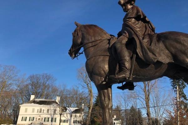 White georgian/colonial building with statue of officer on horse in foreground