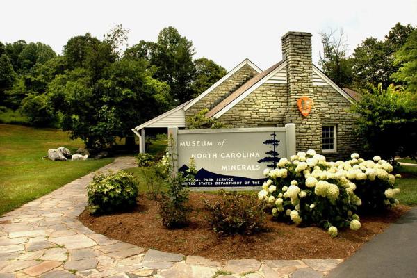 A stone building with an arrowhead logo on it & a sign that says, Museum of North Carolina Minerals