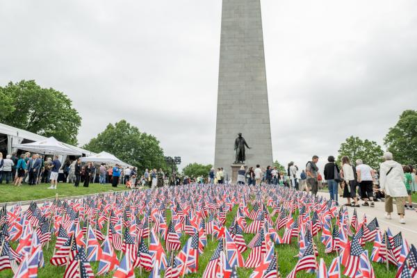 British and American flags planted on the grounds in front of the Bunker Hill Monument