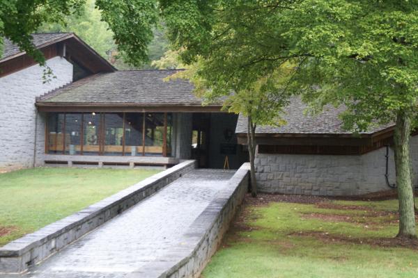 Stone Walkway leading up to Visitor Center. Grass area and trees on both sides of walkway.