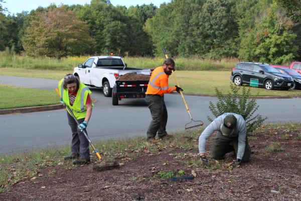 Three people in reflective vests work outdoors