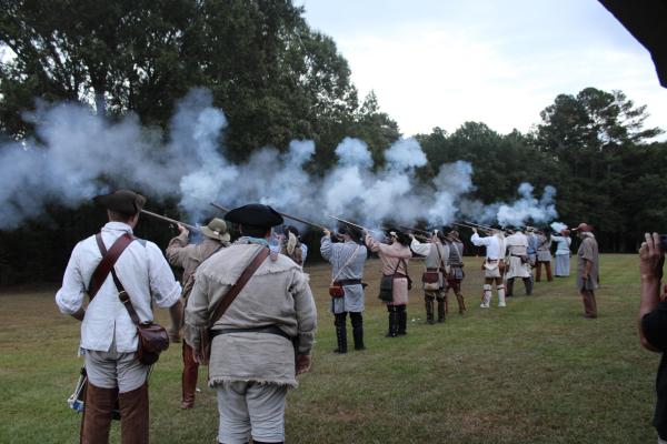 Several reenactors fire muskets