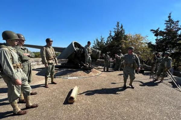 Group of men in uniform beside a historic cannon.