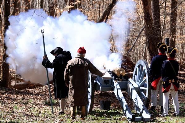 Costumed reenactors standing around a cannon as it is fired