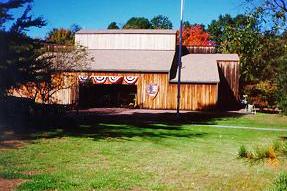 A green lawn leads to a low wooden building with a US flag flying in front