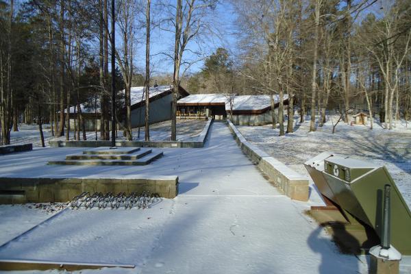 A dusting of snow covers walkway to visitor center in the woods.