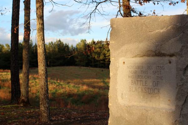 Photograph of a battlefield with a stone marker in the foreground.