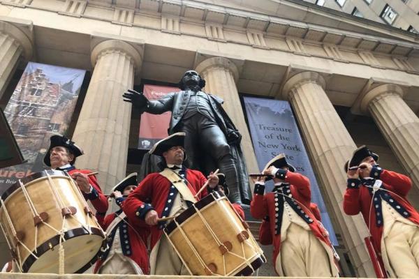 Five men dressed in Revolutionary War outfits play fife and drums
