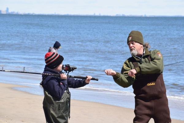 Ranger teaching child how to use fishing equipment