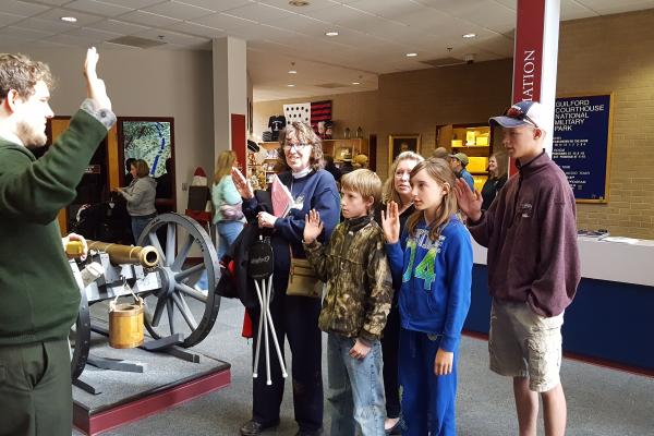 Park Ranger swears in a family of Junior Rangers next to cannon