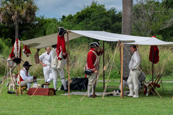 Living historians protraying British soldiers rest under a shelter