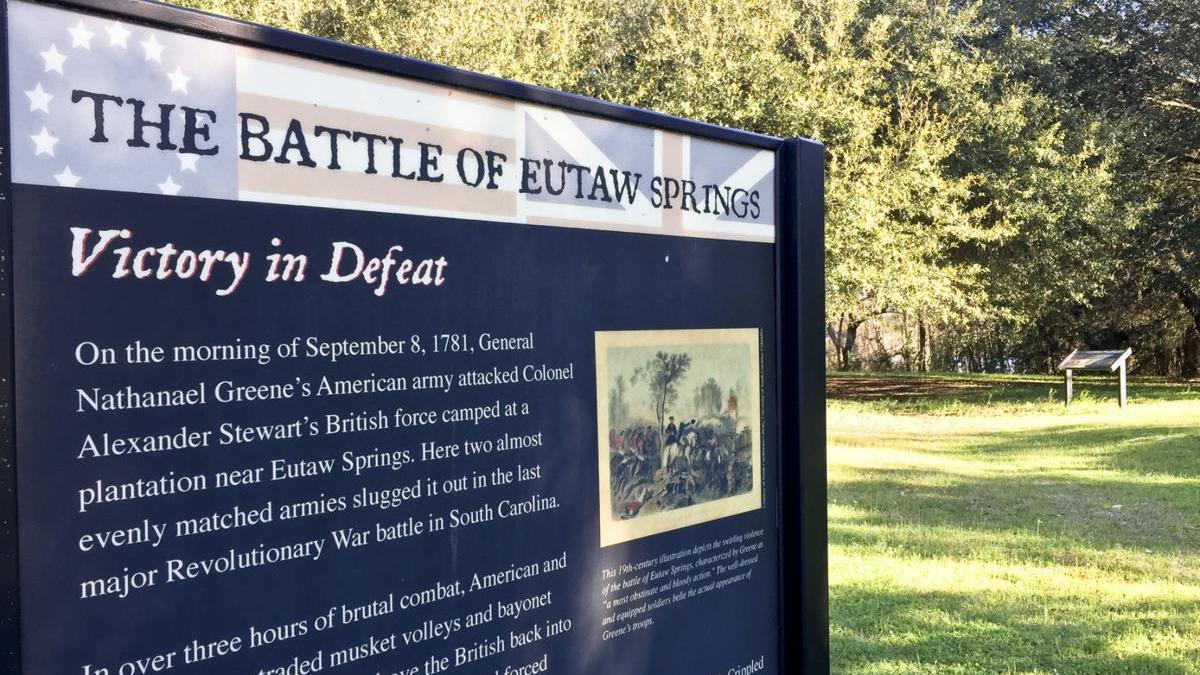A blue park sign denoting the The Battle of Eutaw Springs with white copy on a blue field telling the story of the battle