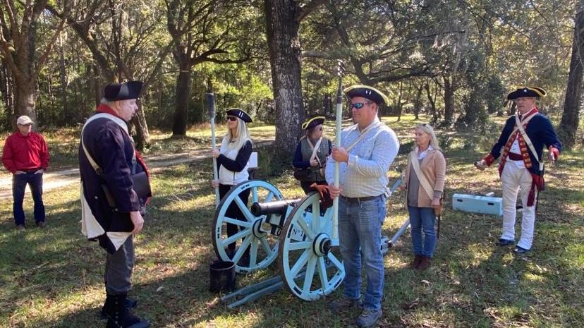 Image of tourists learning to fire a canon from costumed re-enactors