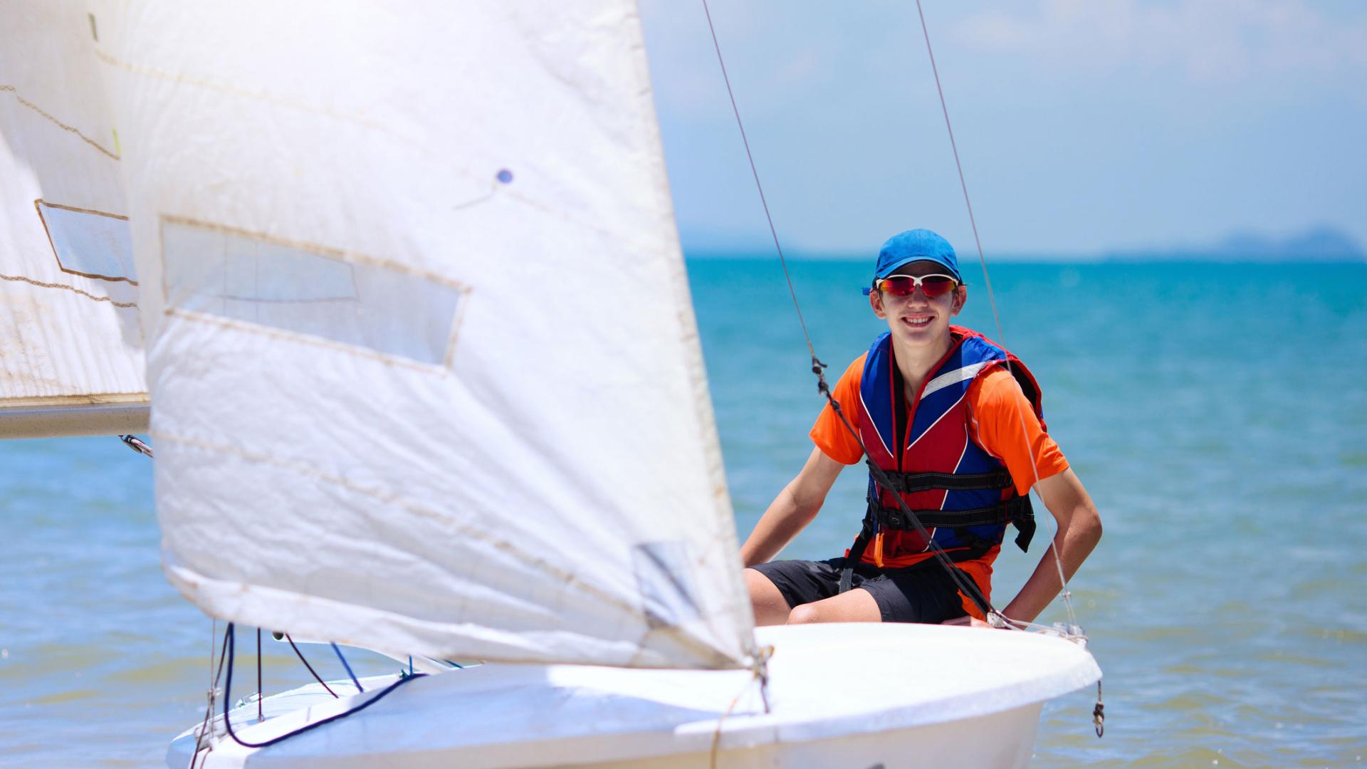 young person on a small sail boat on the water