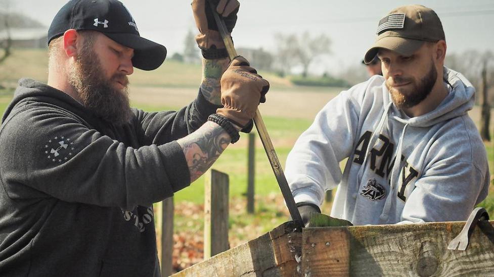2 men working outdoors building a fence