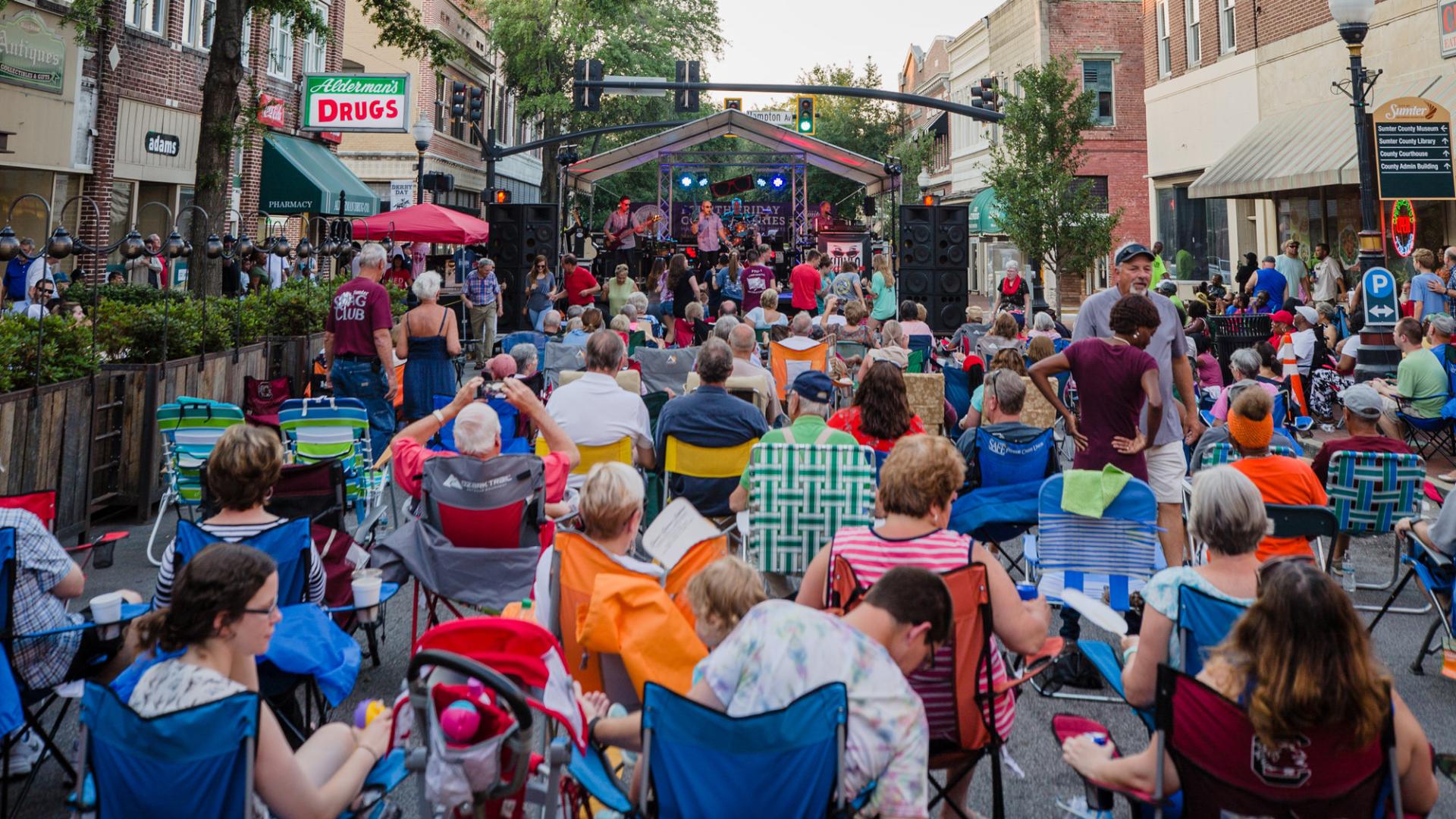 a festival of people in a small town watching a music stage