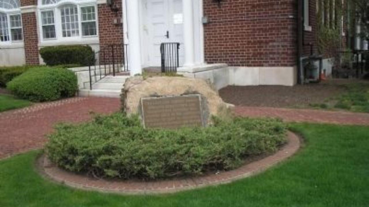 A bronze plaque mounted on a stone surrounded by greenery commemorates a June 23, 1780 militia action that halted a British advance toward Morristown.
