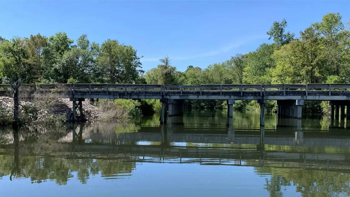 image of bridge over a river with trees and blue sky in the background