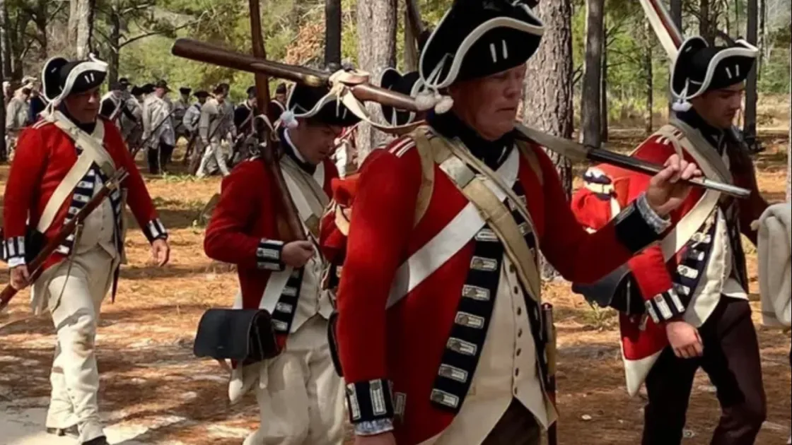 Reenactors march through the pines at the Camden Battlefield