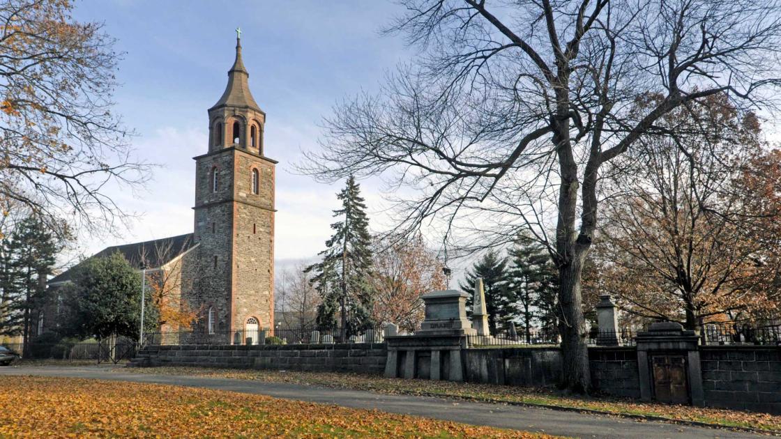 Historic stone church tower surrounded by fall foliage